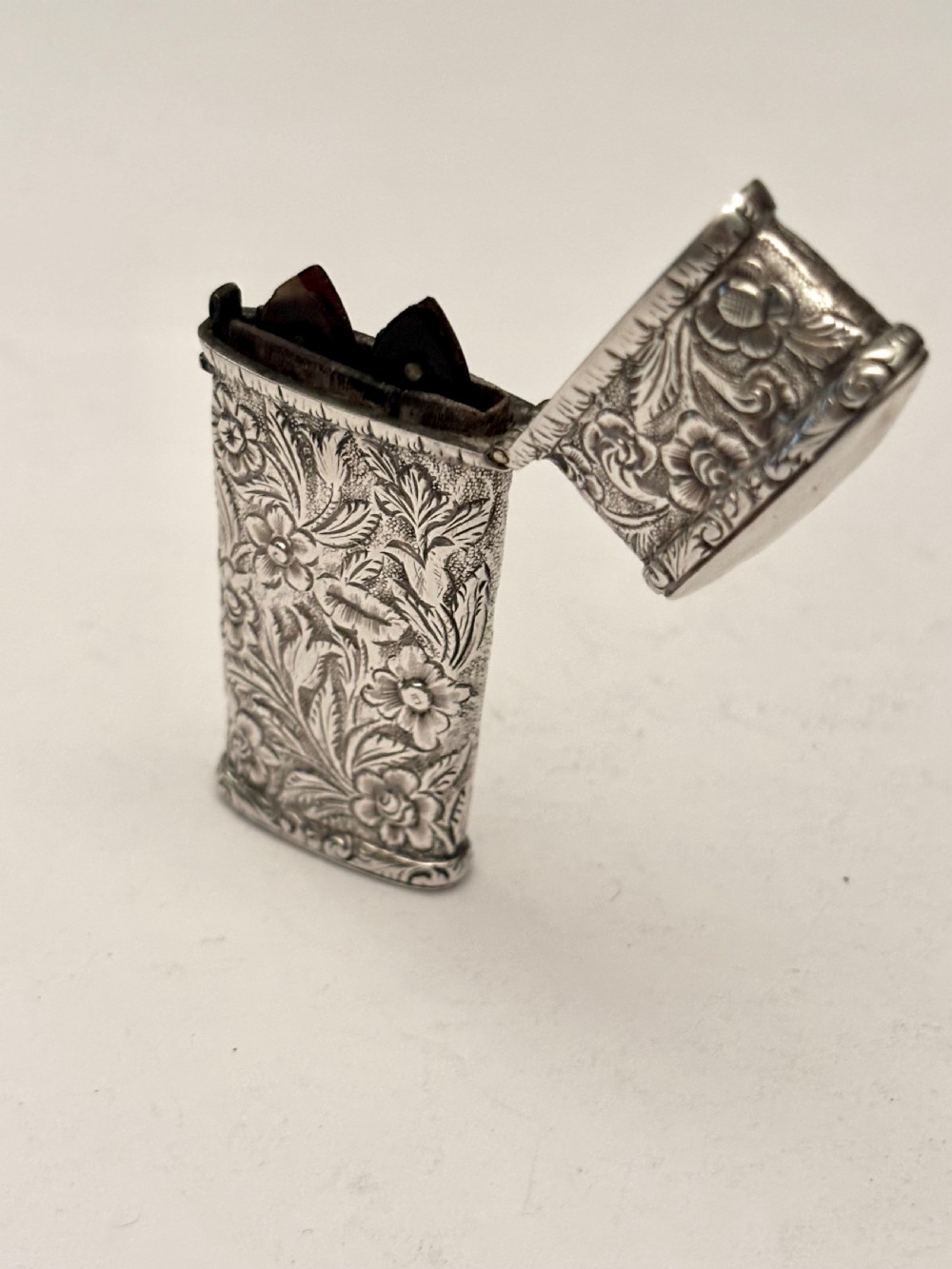 An open William IV sterling silver fleam case with floral chasing, revealing two dark-handled folding blades inside. View XV