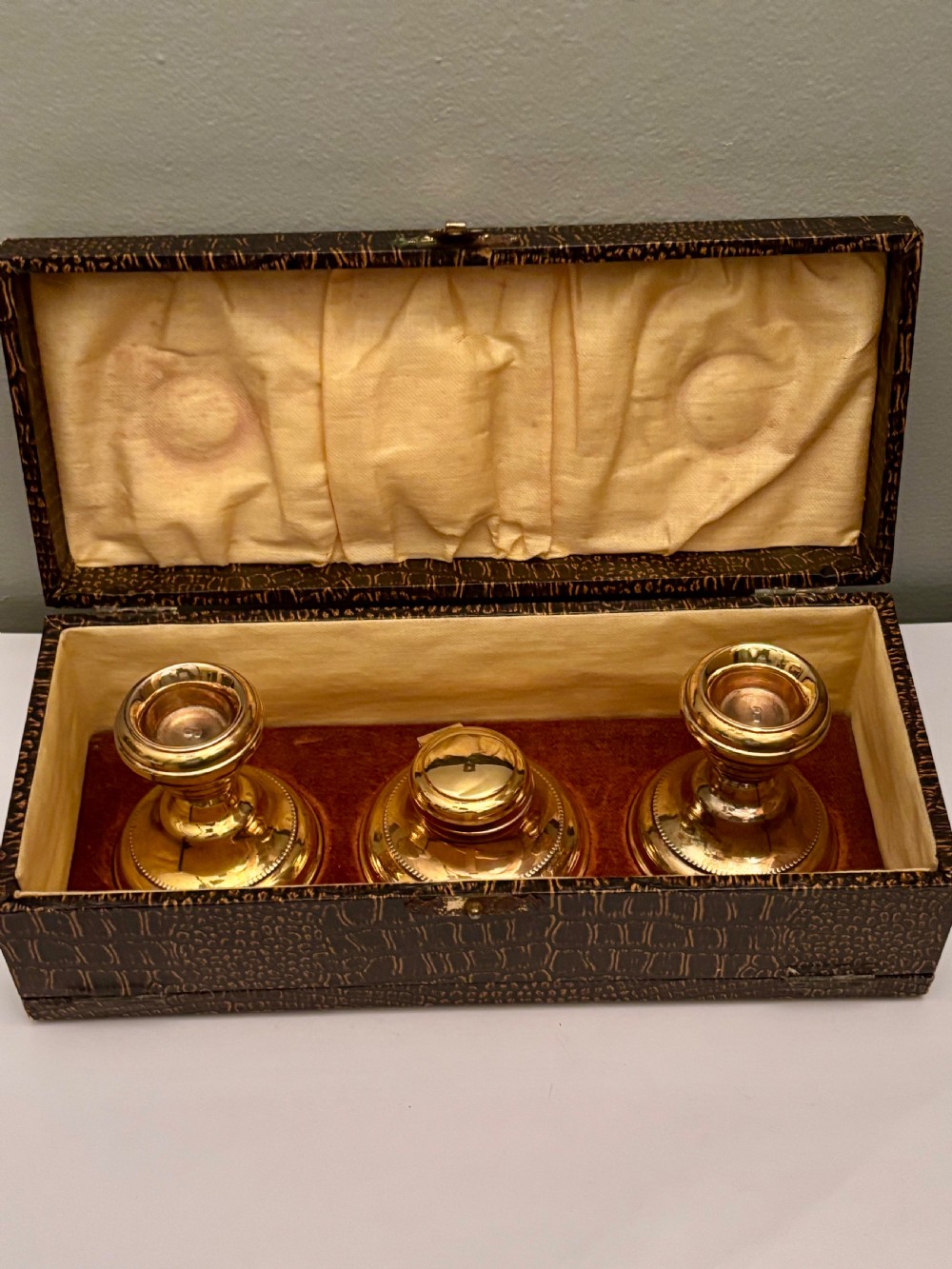 An open fitted presentation box containing two silver gilt candlesticks, a central inkwell, and a dip pen. View II