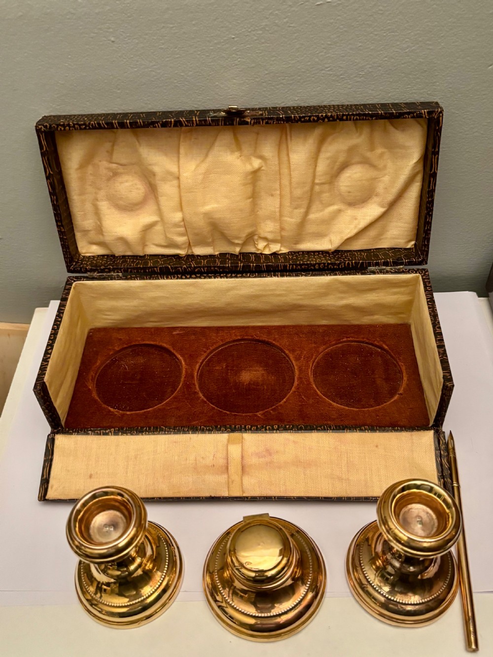 An open fitted presentation box containing two silver gilt candlesticks, a central inkwell, and a dip pen. View III