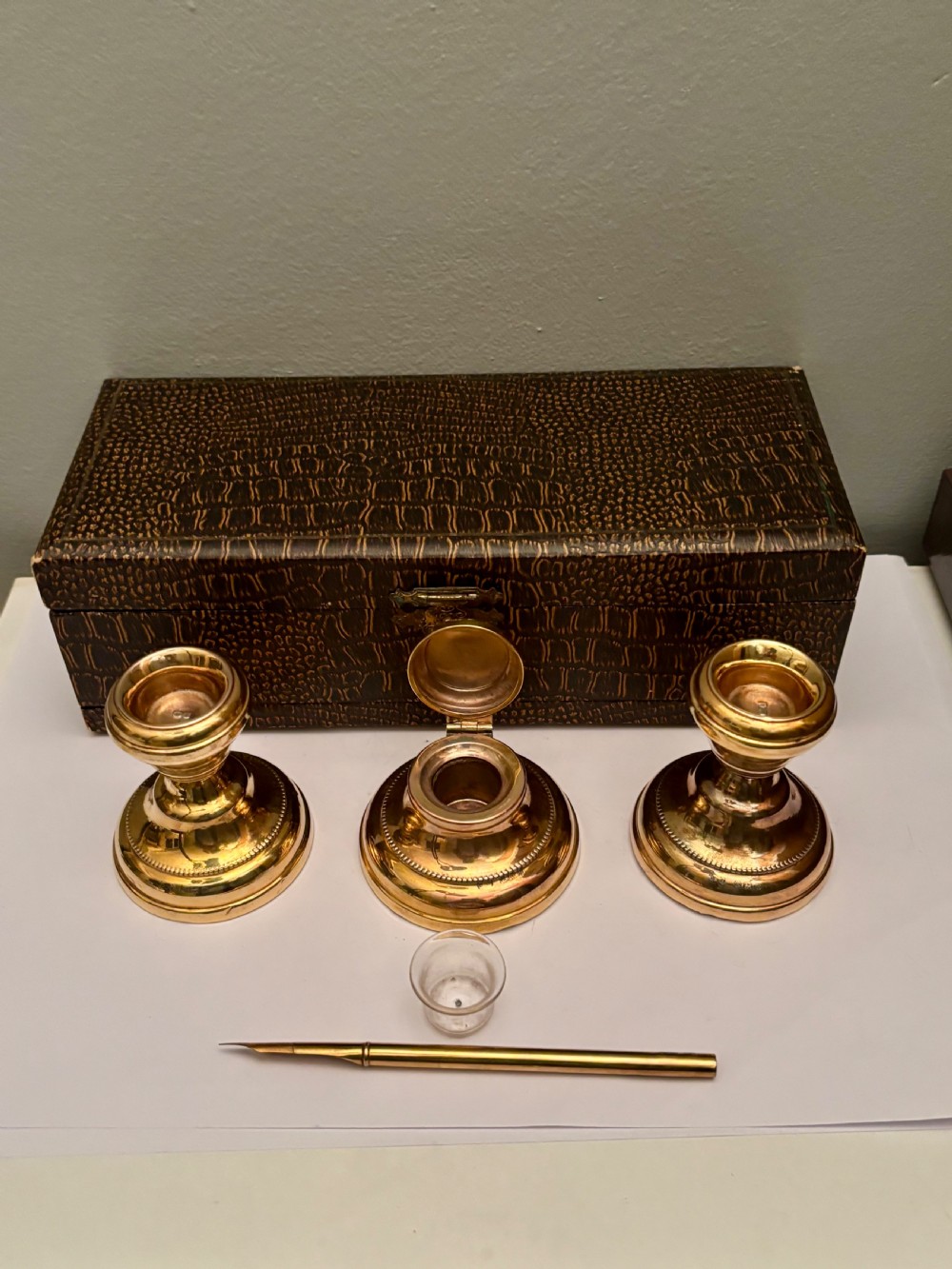 An open fitted presentation box containing two silver gilt candlesticks, a central inkwell, and a dip pen. View VI