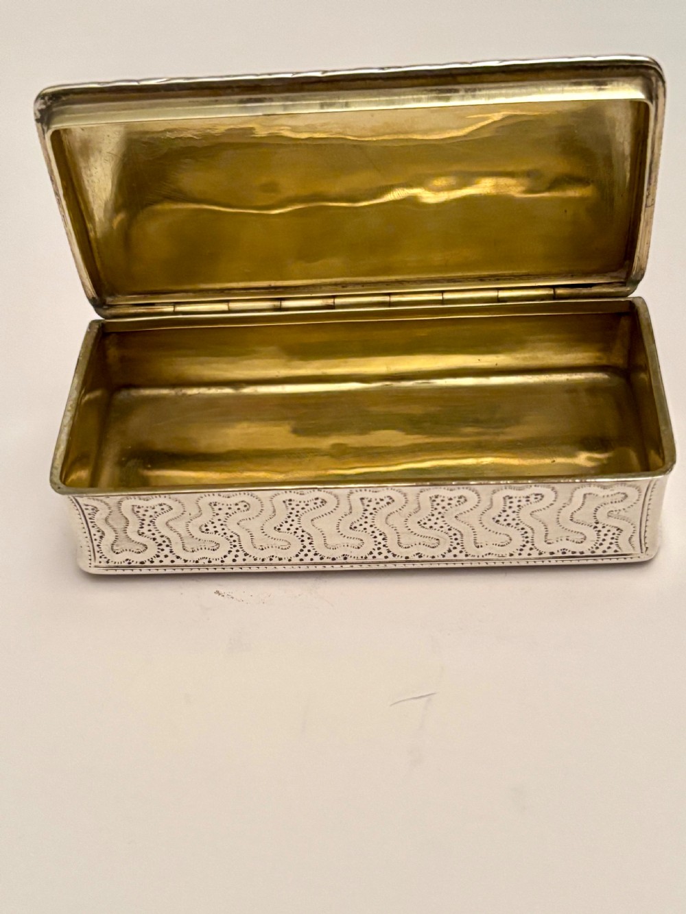 A small rectangular 19th-century French 950 silver gilt snuff box decorated with dense chased scrolling patterns and stippled texture. View III