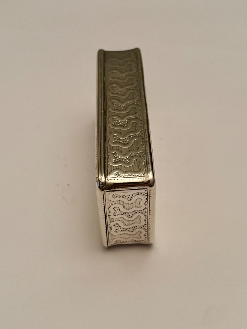 A small rectangular 19th-century French 950 silver gilt snuff box decorated with dense chased scrolling patterns and stippled texture. View IV