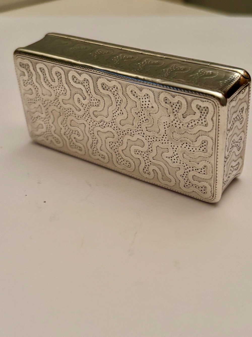 A small rectangular 19th-century French 950 silver gilt snuff box decorated with dense chased scrolling patterns and stippled texture. View VI