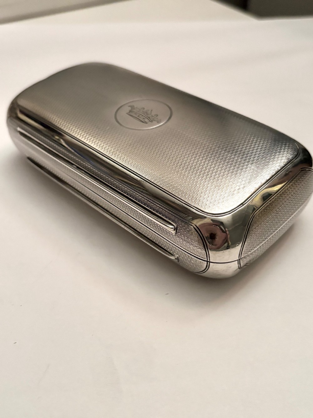 A rectangular Victorian sterling silver box featuring fine engine-turned geometric engraving and a central engraved coronet crest.