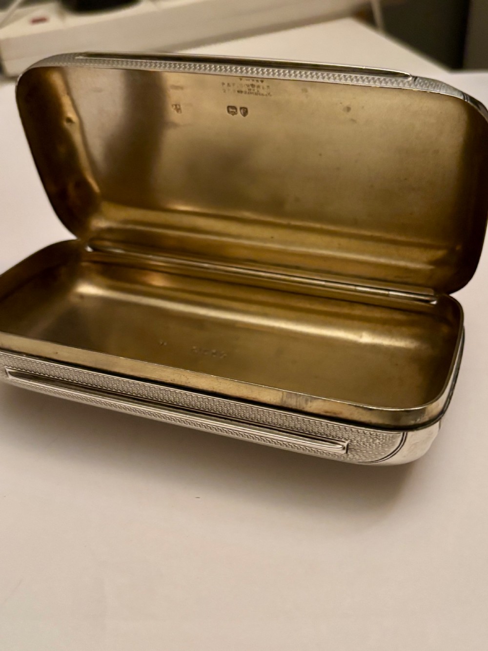 A rectangular Victorian sterling silver box featuring fine engine-turned geometric engraving and a central engraved coronet crest. View XIII
