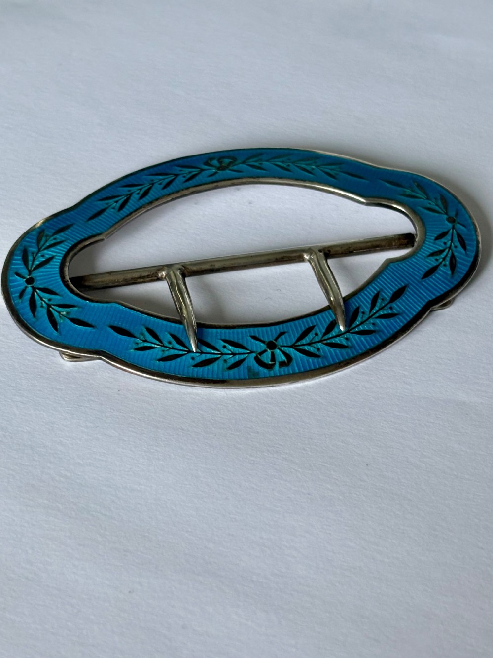 An oval Edwardian sterling silver belt buckle decorated with turquoise blue guilloche enamel and black leaf motifs. View VI