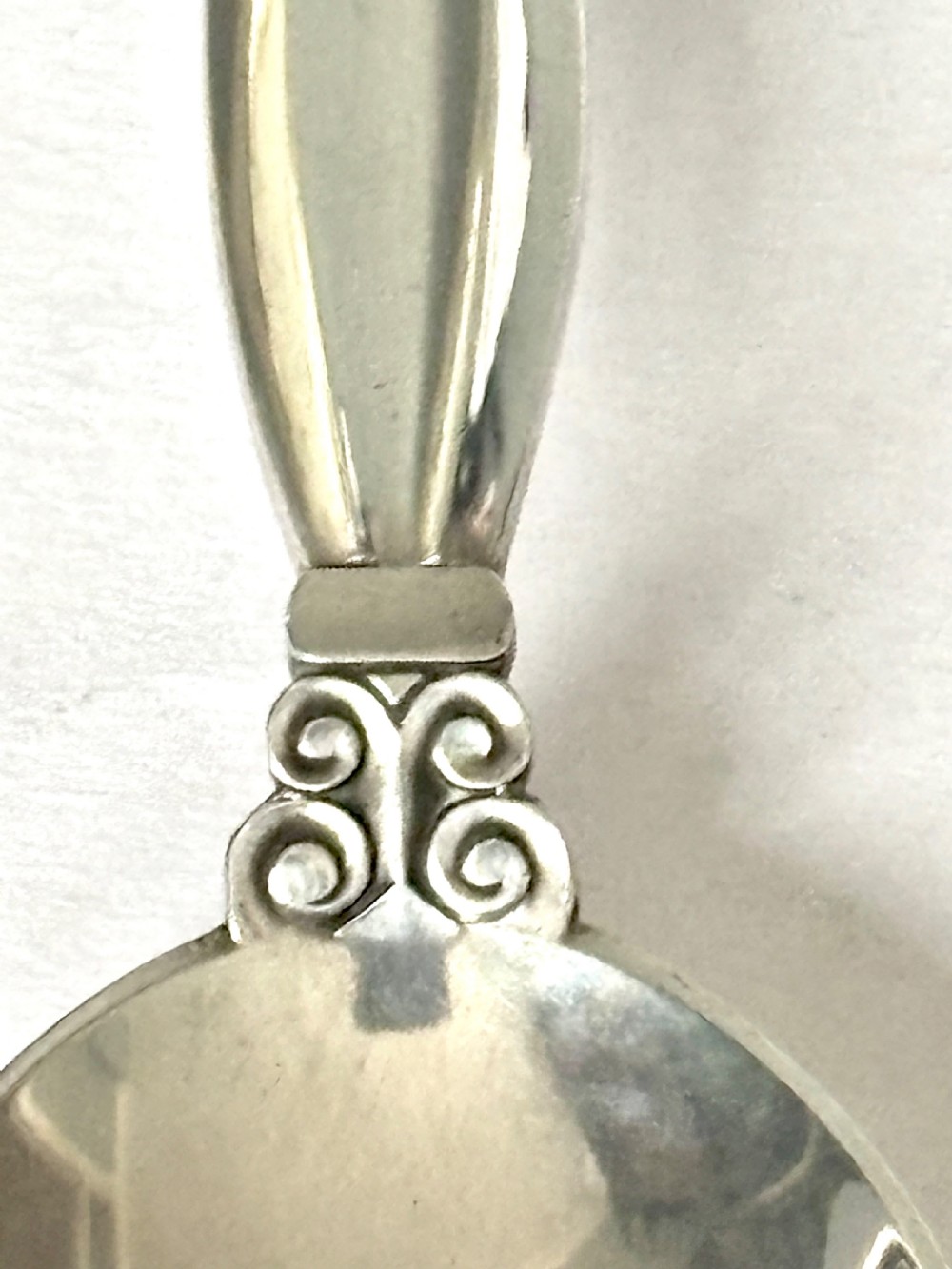 A sterling silver tea caddy spoon featuring a rounded bowl and an acorn motif finial. View III