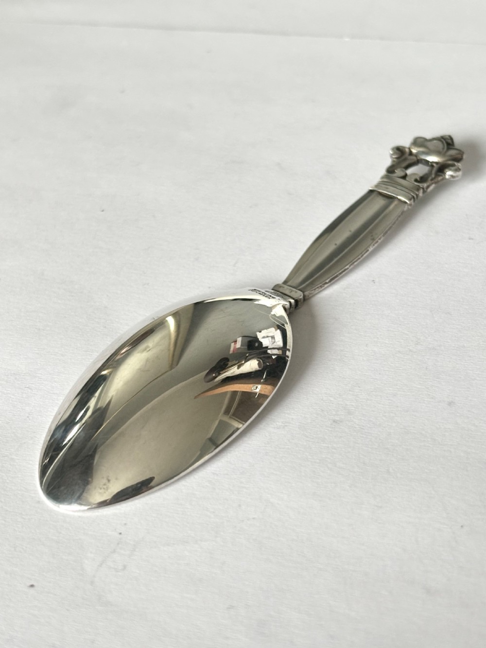 A sterling silver tea caddy spoon featuring a rounded bowl and an acorn motif finial. View V