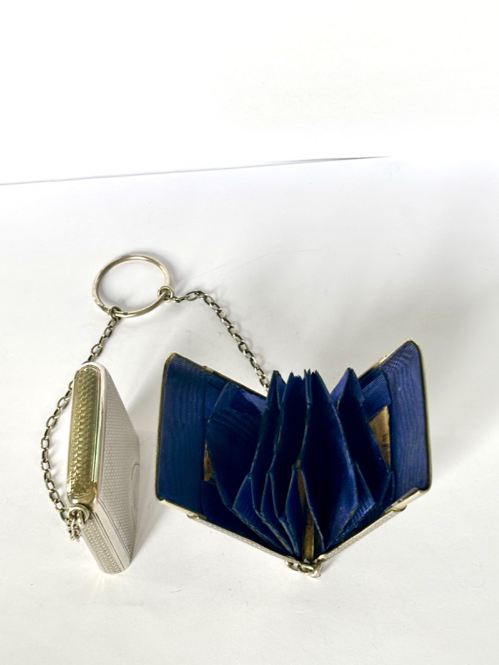 A Victorian sterling silver purse with engine-turned geometric engraving, shown open with a blue silk concertina lining beside a detachable silver case. View VIII