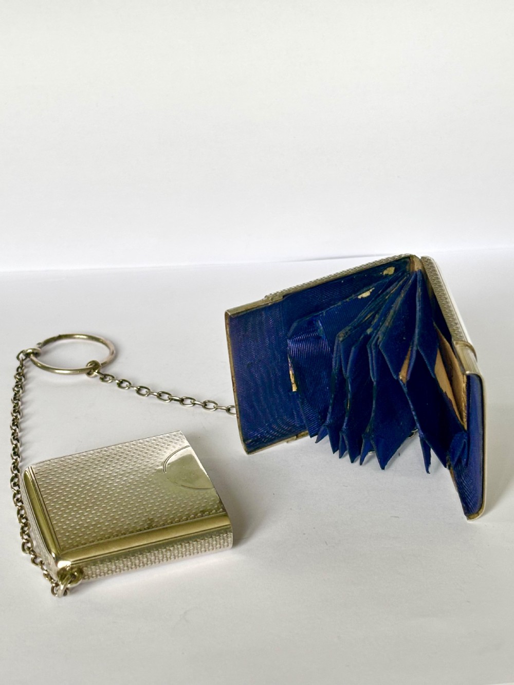 A Victorian sterling silver purse with engine-turned geometric engraving, shown open with a blue silk concertina lining beside a detachable silver case. View IX