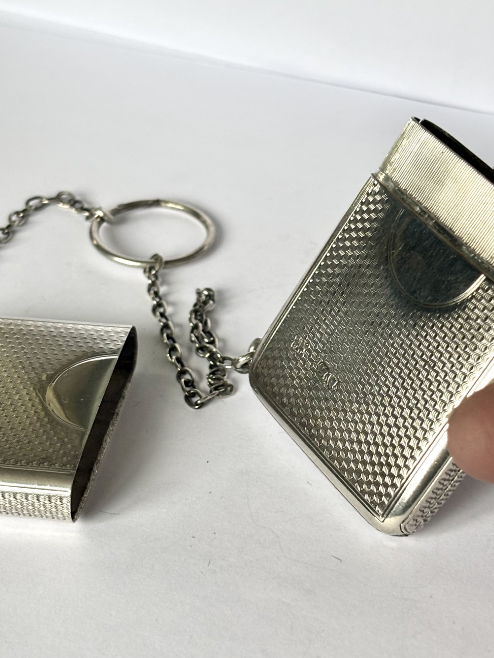 A Victorian sterling silver purse with engine-turned geometric engraving, shown open with a blue silk concertina lining beside a detachable silver case. View X