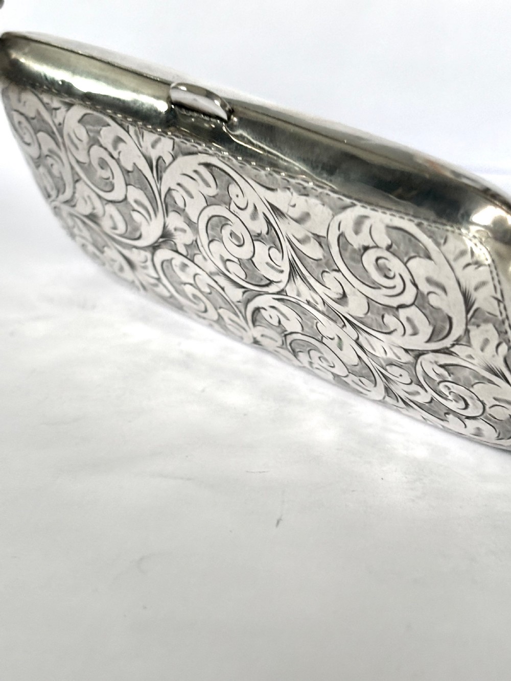 An engraved Art Deco sterling silver purse featuring a fine chain handle, detailed floral scrollwork, and a central polished oval cartouche. View II