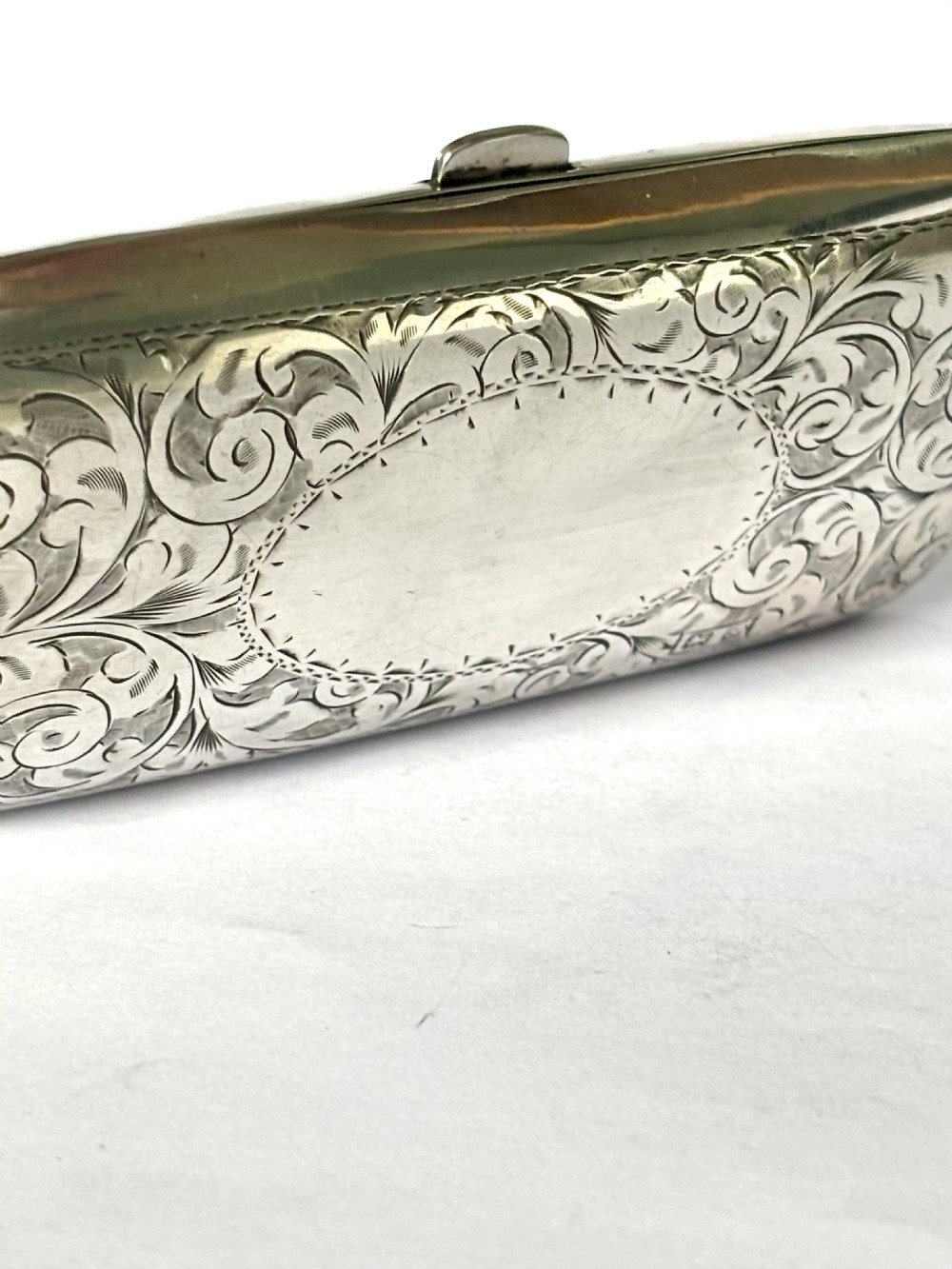 An engraved Art Deco sterling silver purse featuring a fine chain handle, detailed floral scrollwork, and a central polished oval cartouche. View III