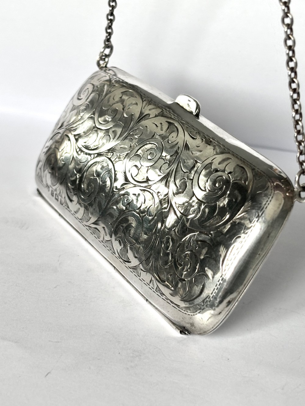 An engraved Art Deco sterling silver purse featuring a fine chain handle, detailed floral scrollwork, and a central polished oval cartouche. View VI
