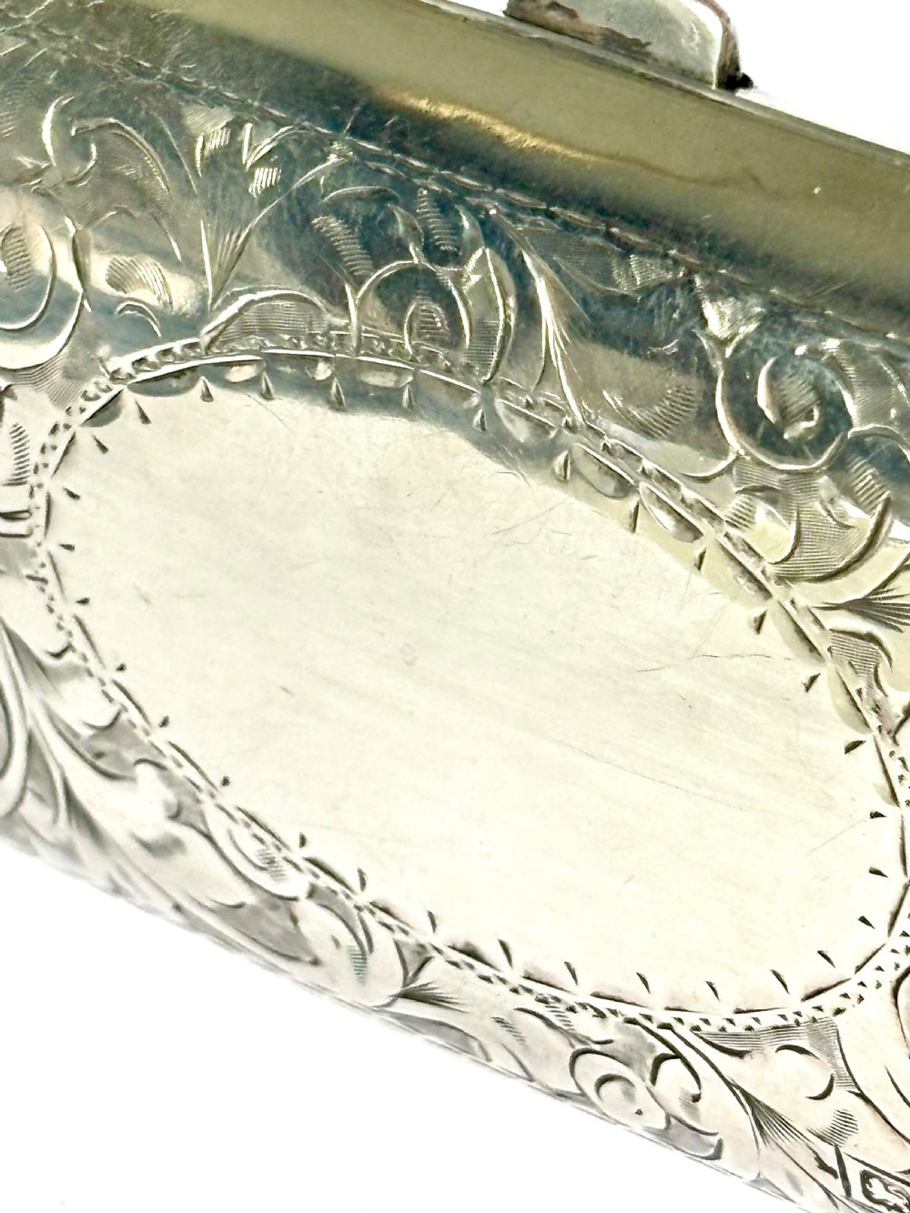An engraved Art Deco sterling silver purse featuring a fine chain handle, detailed floral scrollwork, and a central polished oval cartouche. View VIII