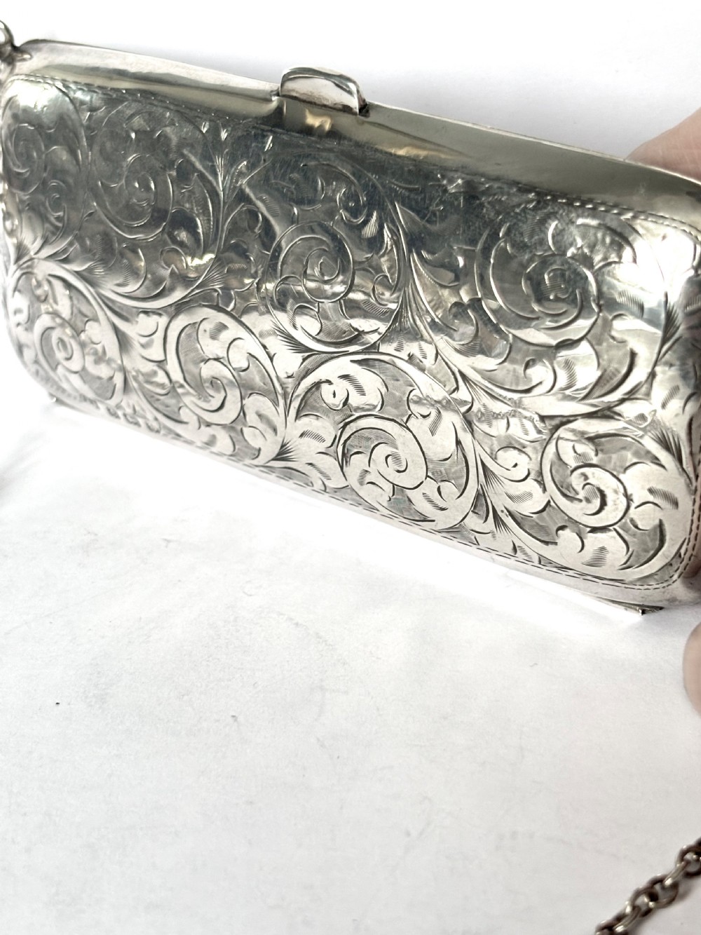 An engraved Art Deco sterling silver purse featuring a fine chain handle, detailed floral scrollwork, and a central polished oval cartouche. View IX
