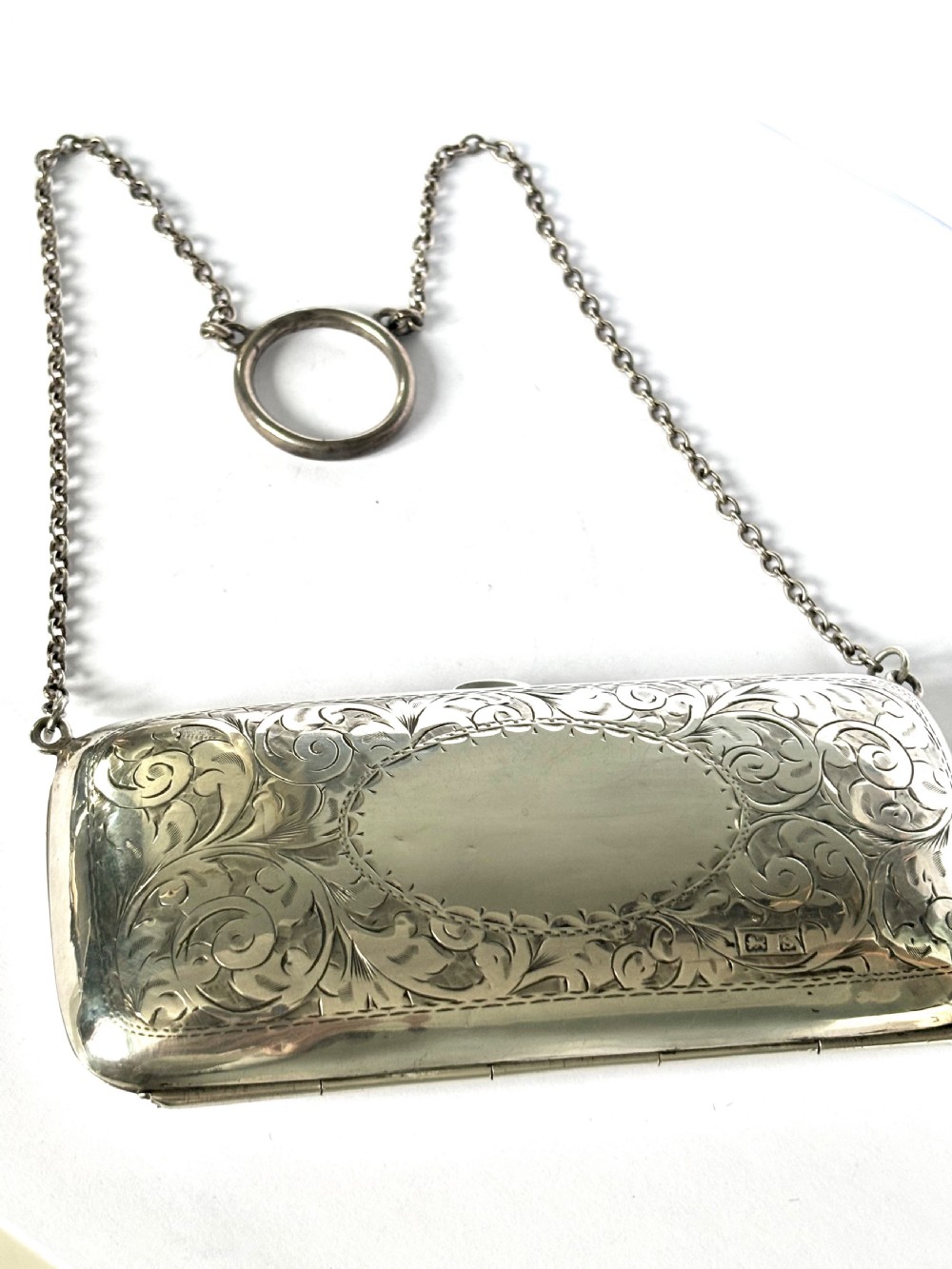 An engraved Art Deco sterling silver purse featuring a fine chain handle, detailed floral scrollwork, and a central polished oval cartouche. View XI