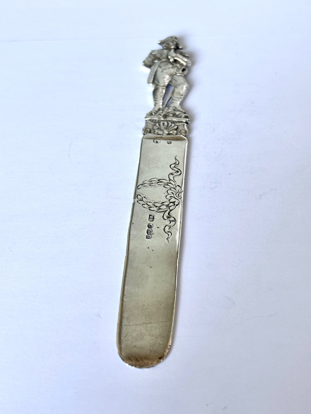 An Edwardian sterling silver letter opener featuring a cast figure of Napoleon on the handle and an engraved laurel wreath on the blade.