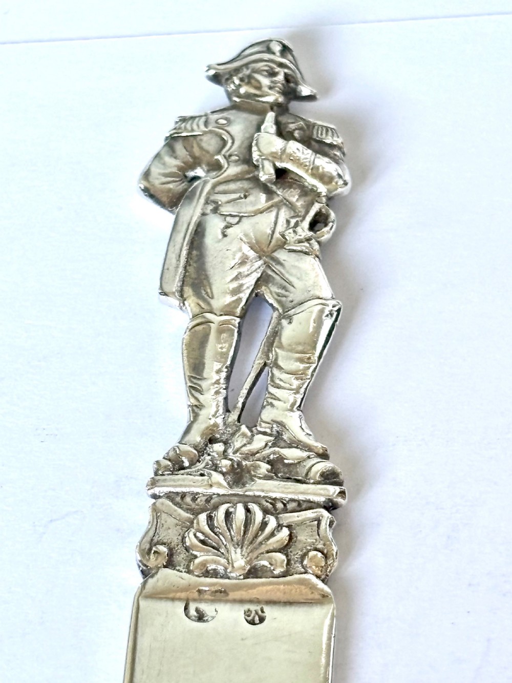 An Edwardian sterling silver letter opener featuring a cast figure of Napoleon on the handle and an engraved laurel wreath on the blade. View V