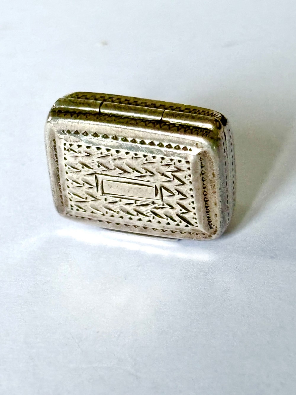 A rectangular George IV sterling silver vinaigrette with engine-turned geometric engraving and a blank central cartouche.