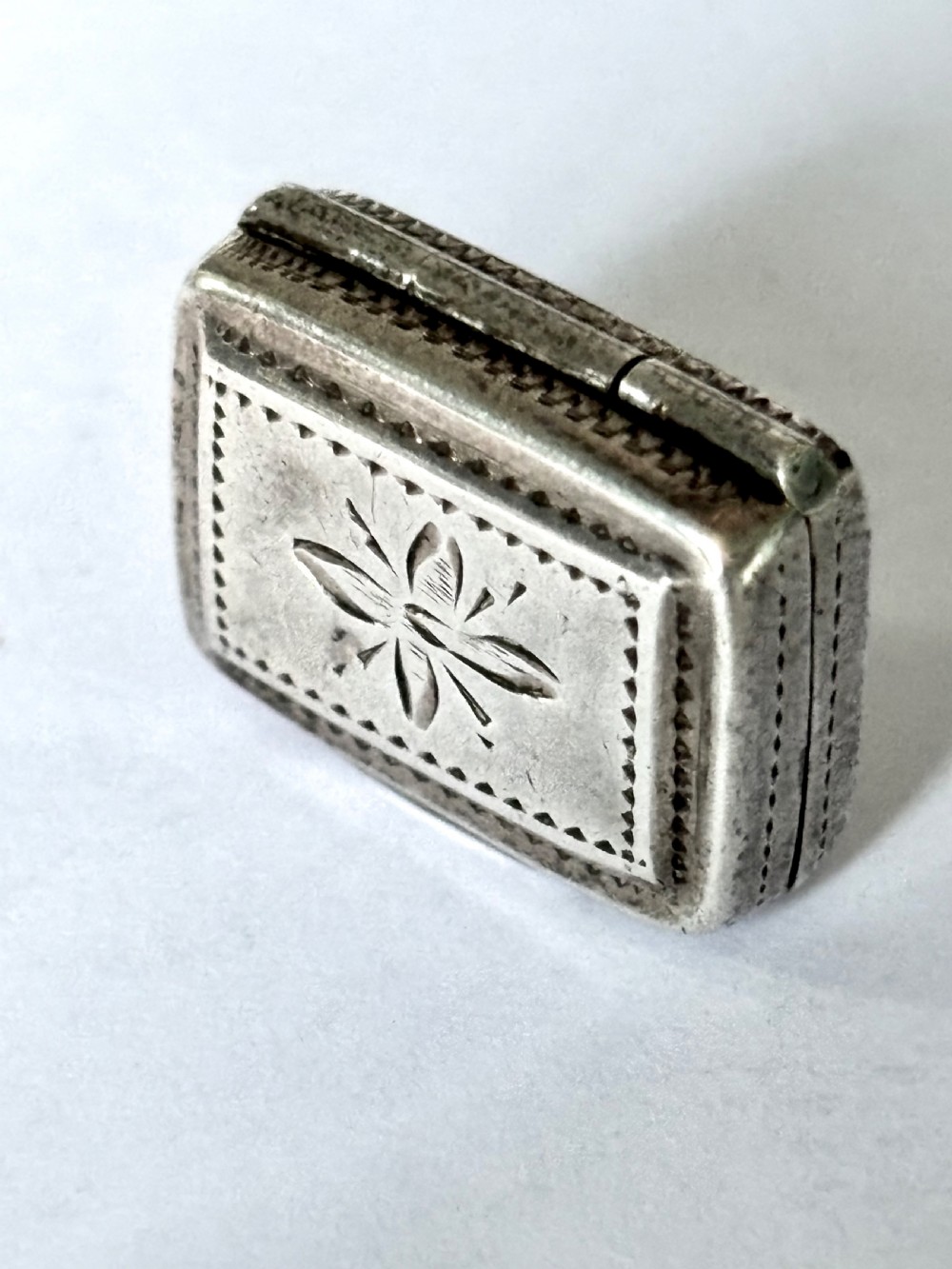 A rectangular George IV sterling silver vinaigrette with engine-turned geometric engraving and a blank central cartouche. View II