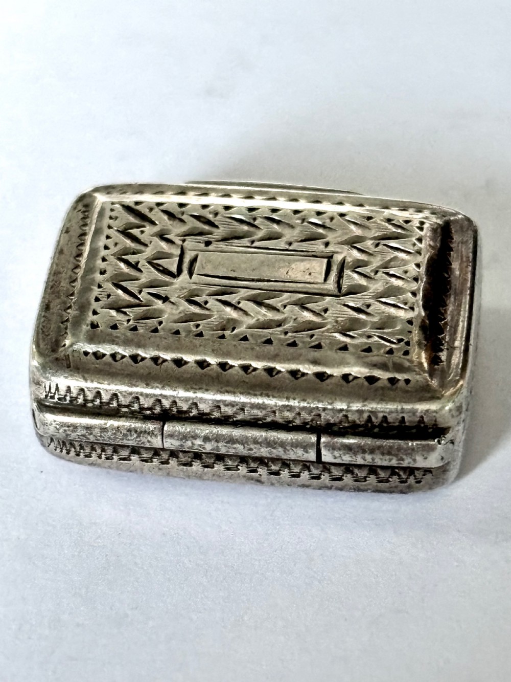A rectangular George IV sterling silver vinaigrette with engine-turned geometric engraving and a blank central cartouche. View IX