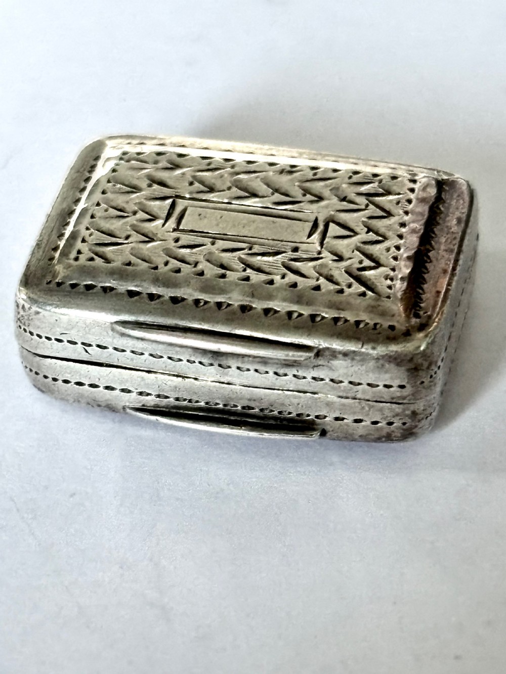 A rectangular George IV sterling silver vinaigrette with engine-turned geometric engraving and a blank central cartouche. View X