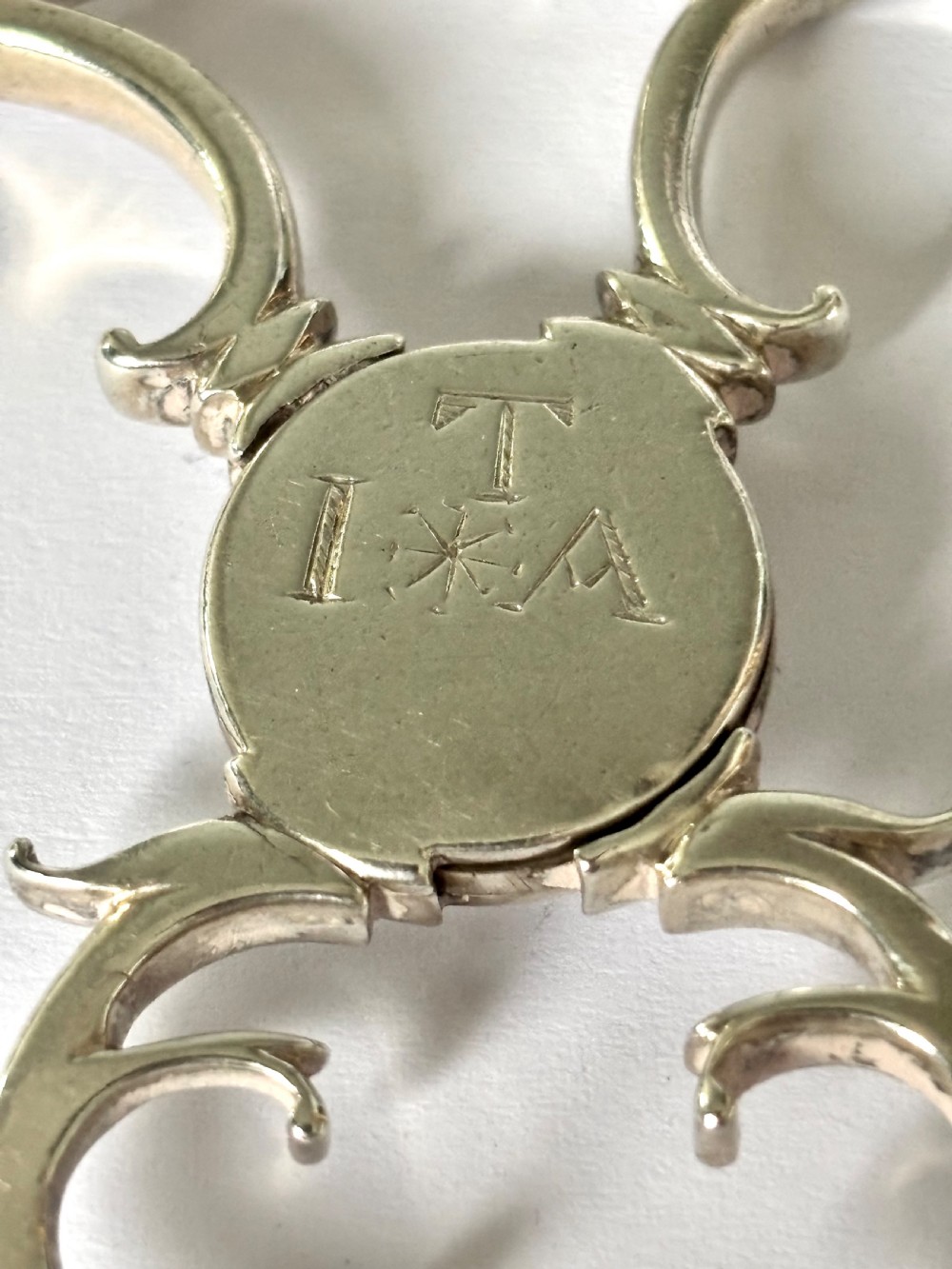 A pair of Georgian sterling silver sugar nips featuring scissor-action finger loops, scroll arms, and shell-shaped grips. View VII