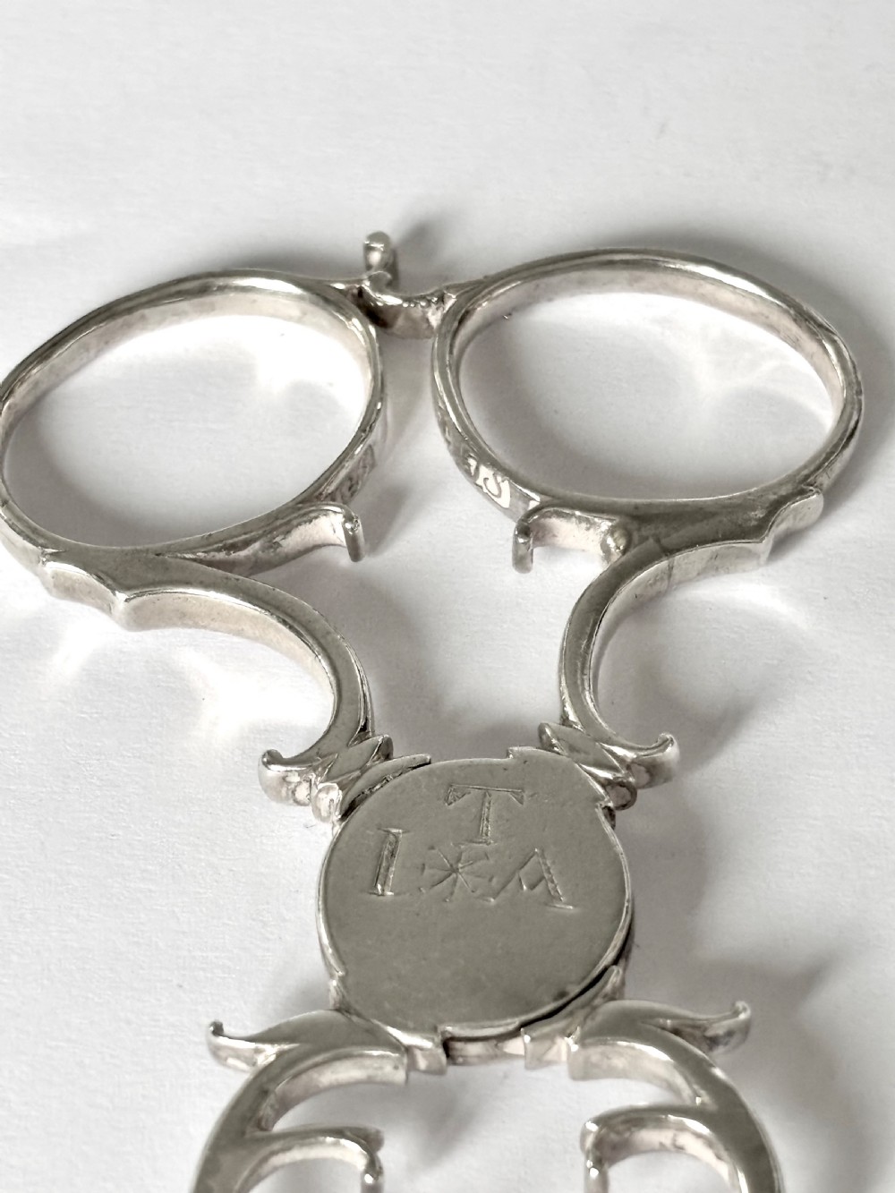 A pair of Georgian sterling silver sugar nips featuring scissor-action finger loops, scroll arms, and shell-shaped grips. View VIII
