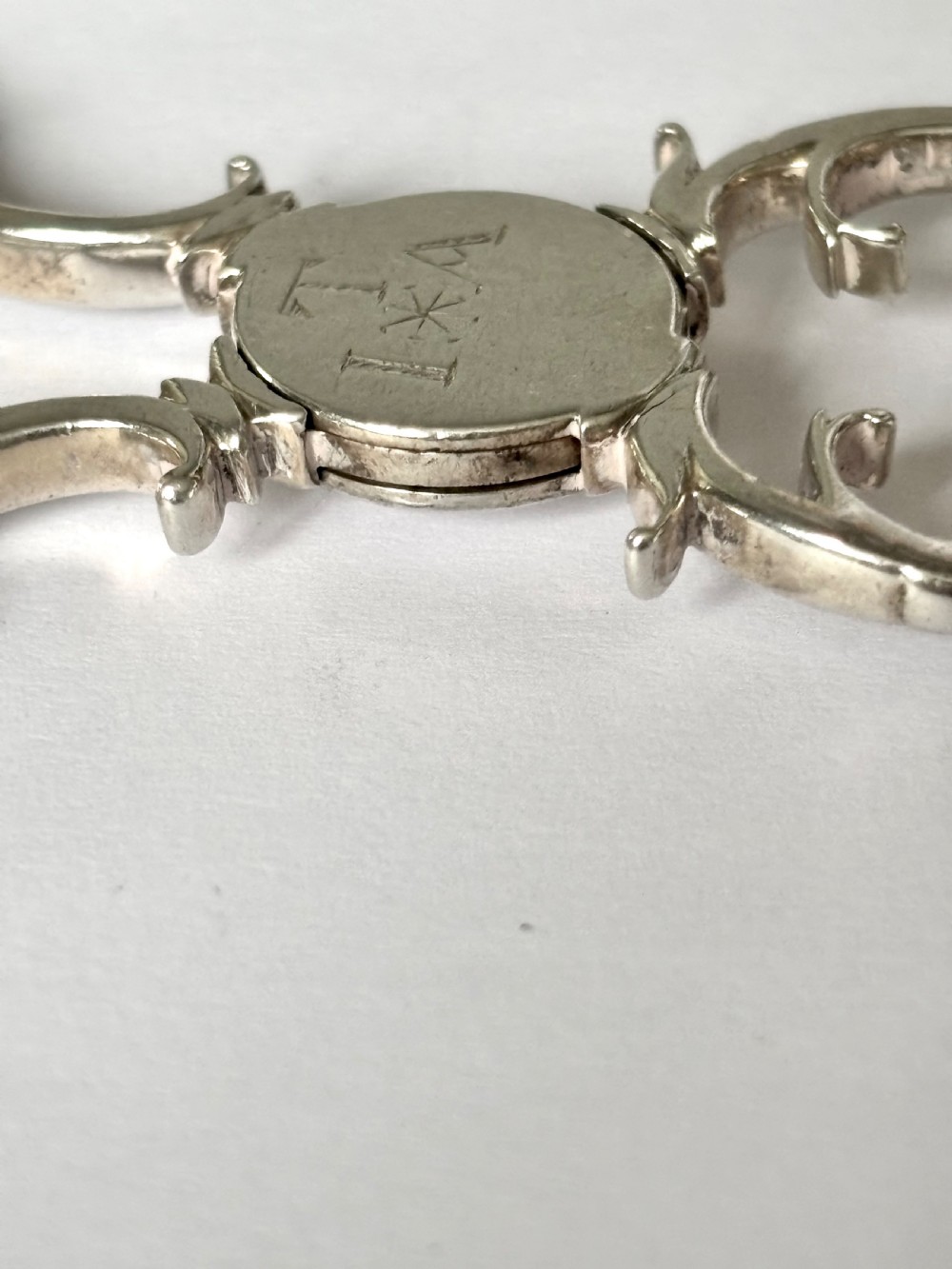 A pair of Georgian sterling silver sugar nips featuring scissor-action finger loops, scroll arms, and shell-shaped grips. View X