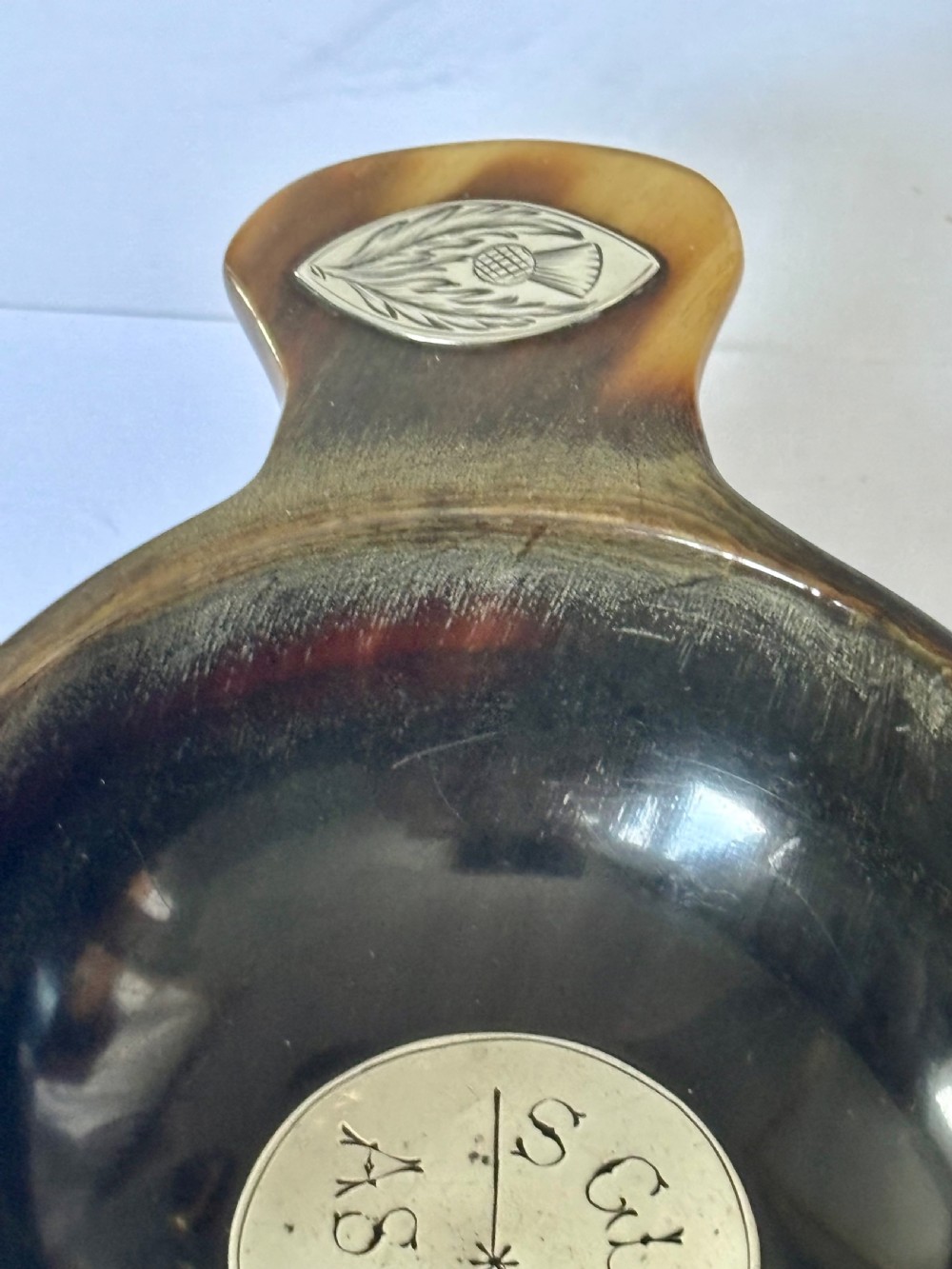 An antique Scottish horn quaich featuring carved lug handles with hallmarked silver thistle and Celtic cross mounts, and an inscribed silver central boss inside the bowl. View V