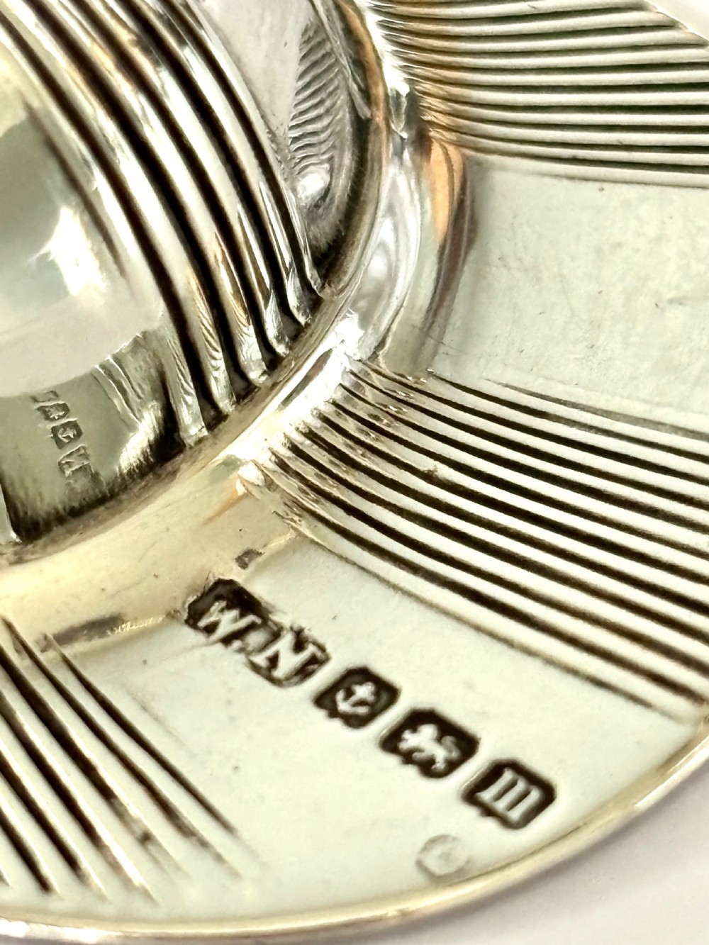 A solid sterling silver caddy spoon shaped like a peaked jockey cap with fluted panel detailing and British hallmarks along the brim. View III