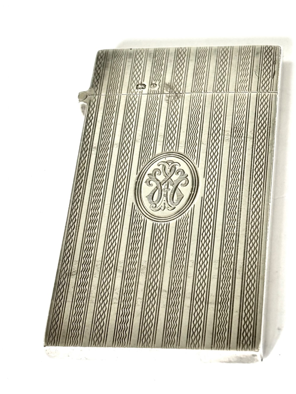 An Edwardian sterling silver slimline calling card case featuring vertical engine-turned stripes and a central oval monogram cartouche. View IV
