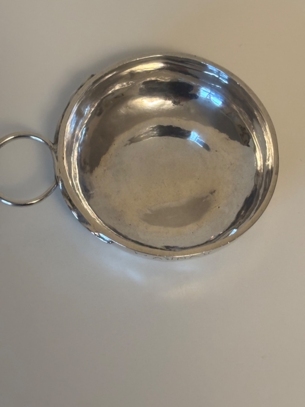 A shallow 19th-century French silver wine taster featuring a loop handle and engraved lettering on the outer rim. View II