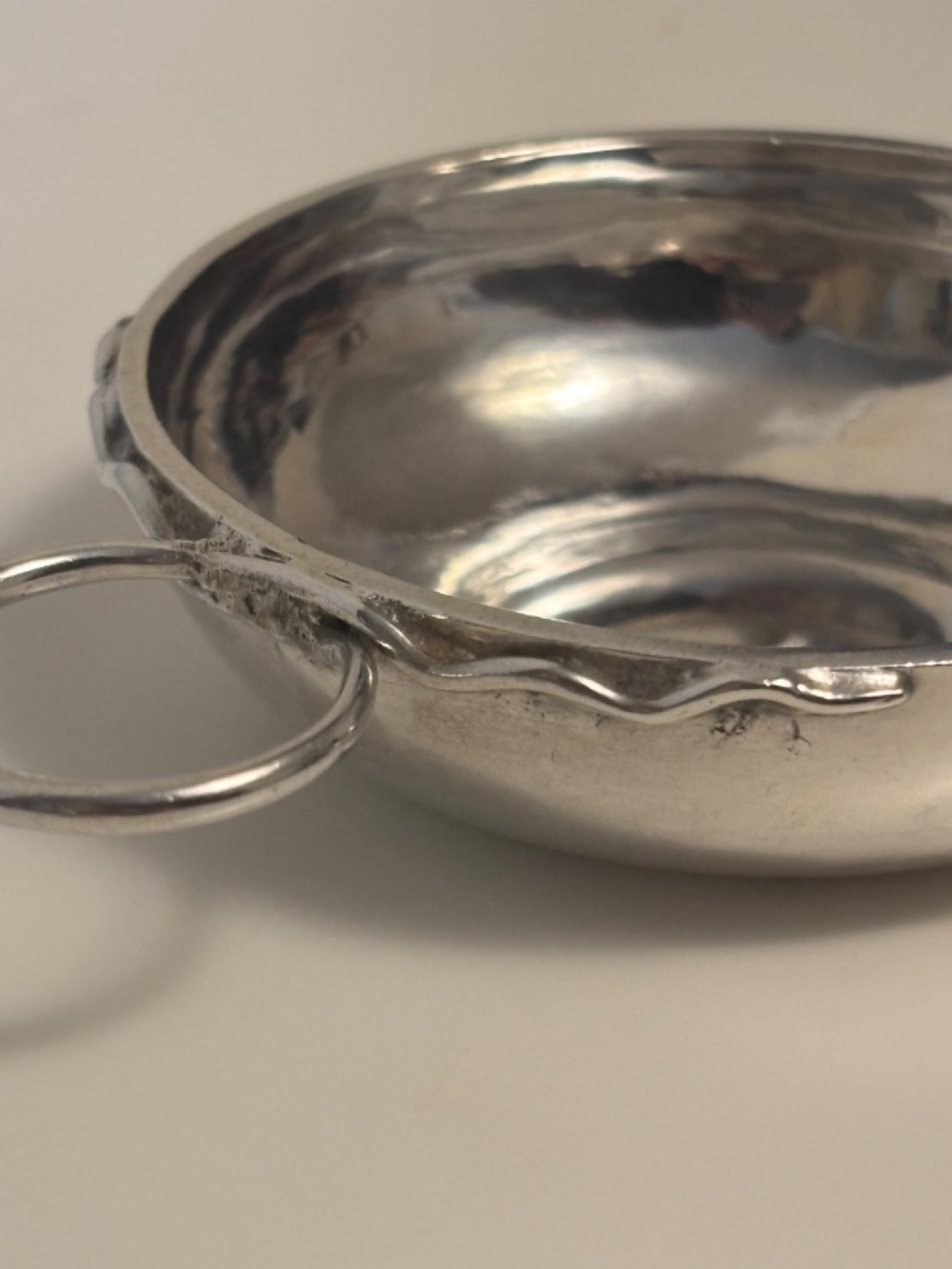 A shallow 19th-century French silver wine taster featuring a loop handle and engraved lettering on the outer rim. View V