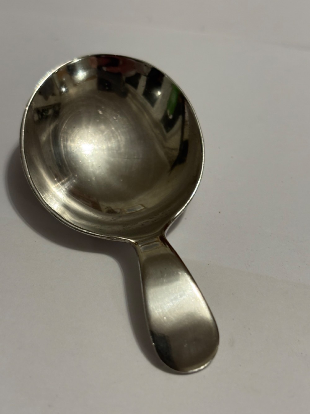 A George III sterling silver caddy spoon featuring a rounded bowl and a plain, short handle.