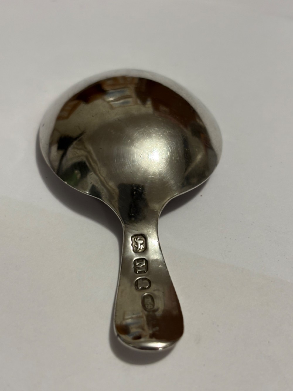 A George III sterling silver caddy spoon featuring a rounded bowl and a plain, short handle. View II