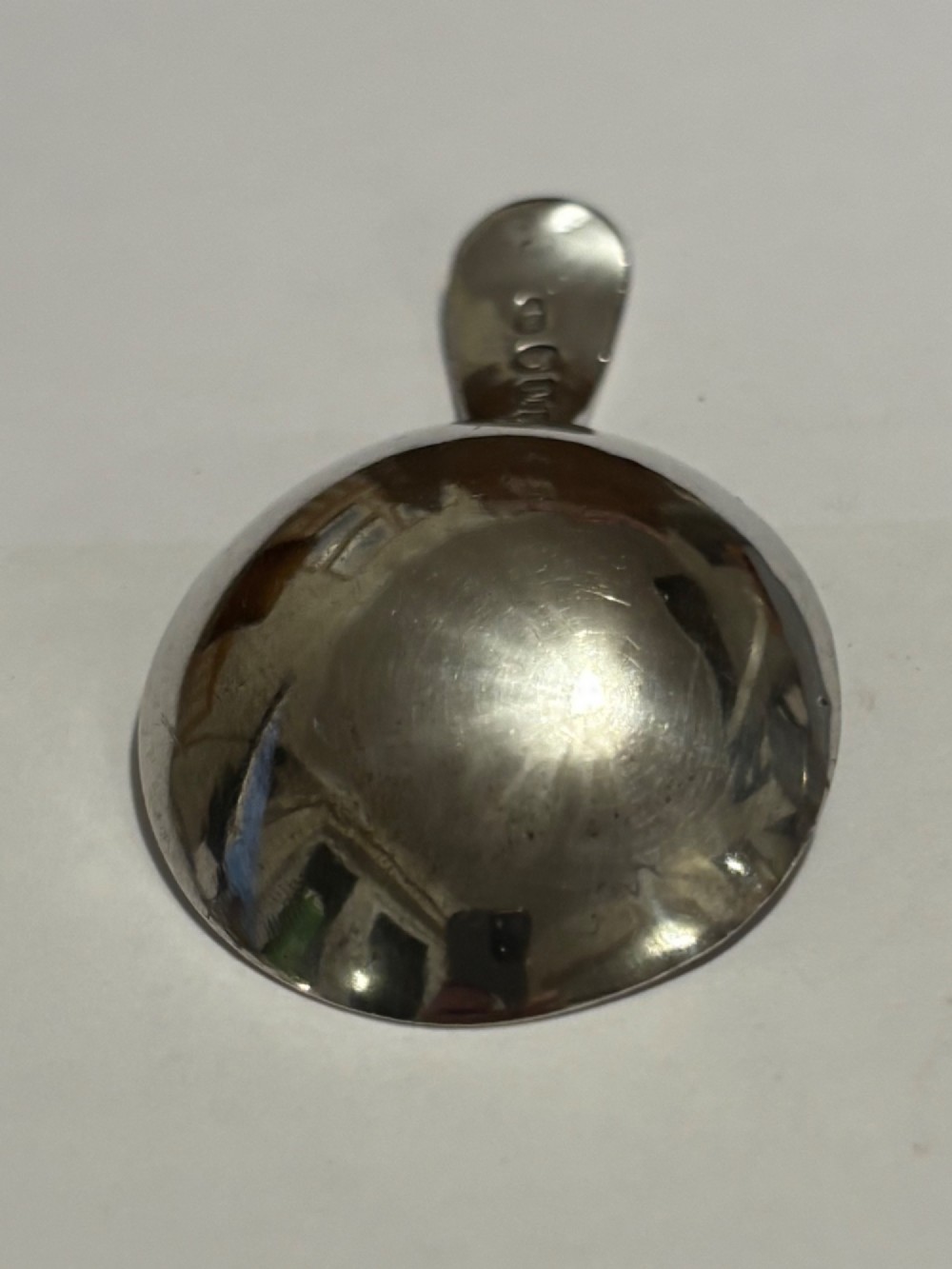 A George III sterling silver caddy spoon featuring a rounded bowl and a plain, short handle. View IV