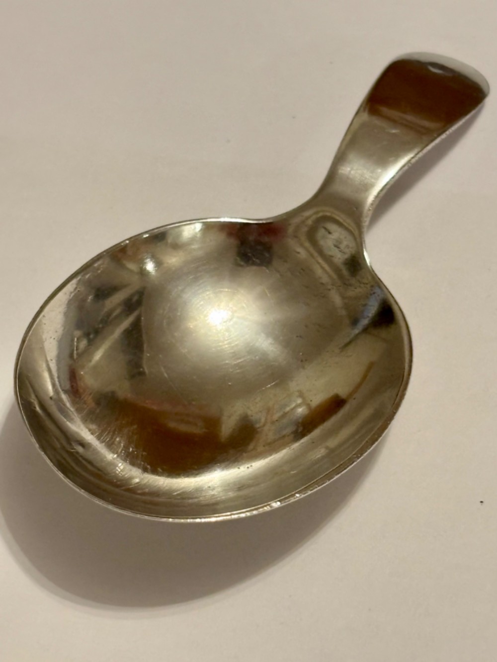 A George III sterling silver caddy spoon featuring a rounded bowl and a plain, short handle. View VI