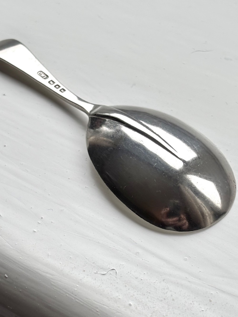 Underside view of a George V hallmarked sterling silver caddy spoon featuring a plain oval bowl and stamped hallmarks along the handle stem.