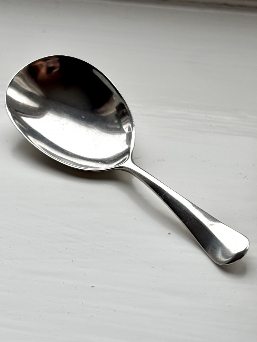 Underside view of a George V hallmarked sterling silver caddy spoon featuring a plain oval bowl and stamped hallmarks along the handle stem. View II