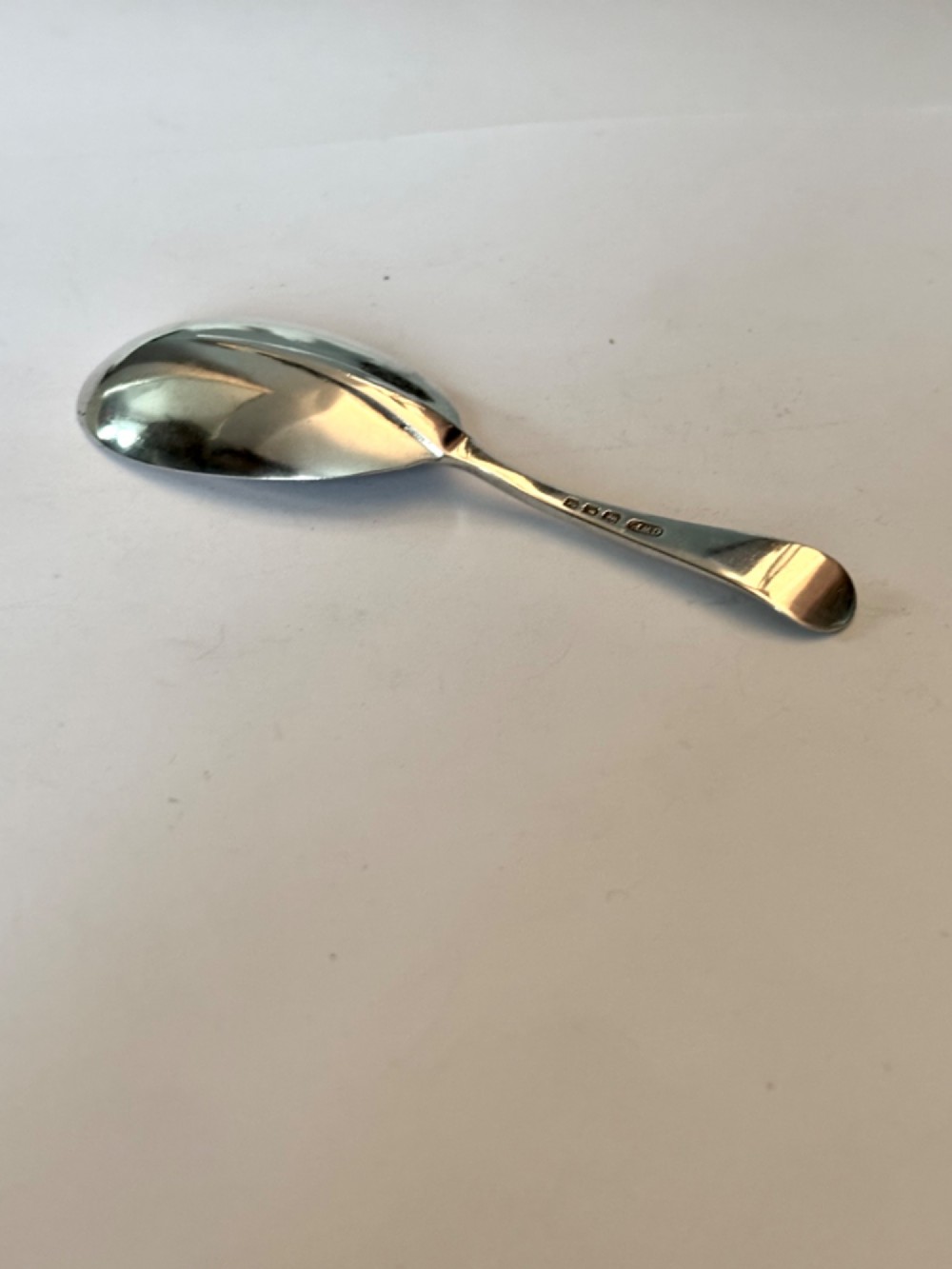 Underside view of a George V hallmarked sterling silver caddy spoon featuring a plain oval bowl and stamped hallmarks along the handle stem. View IV