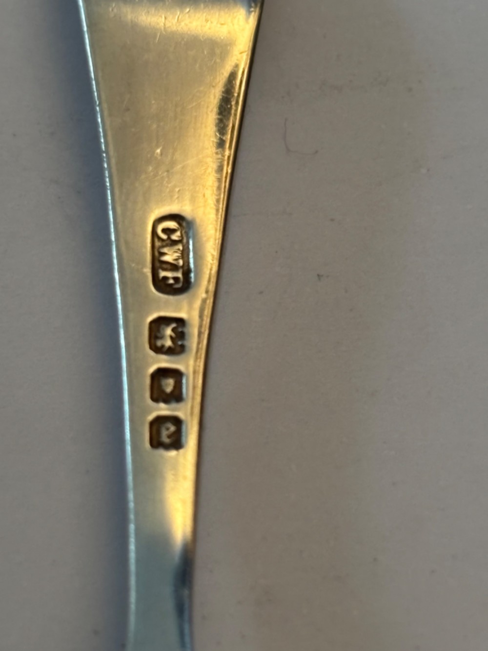 Underside view of a George V hallmarked sterling silver caddy spoon featuring a plain oval bowl and stamped hallmarks along the handle stem. View V