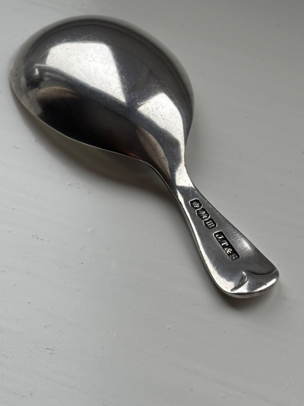 A George V sterling silver tea caddy spoon with a wide oval bowl and an engraved monogrammed handle. View II