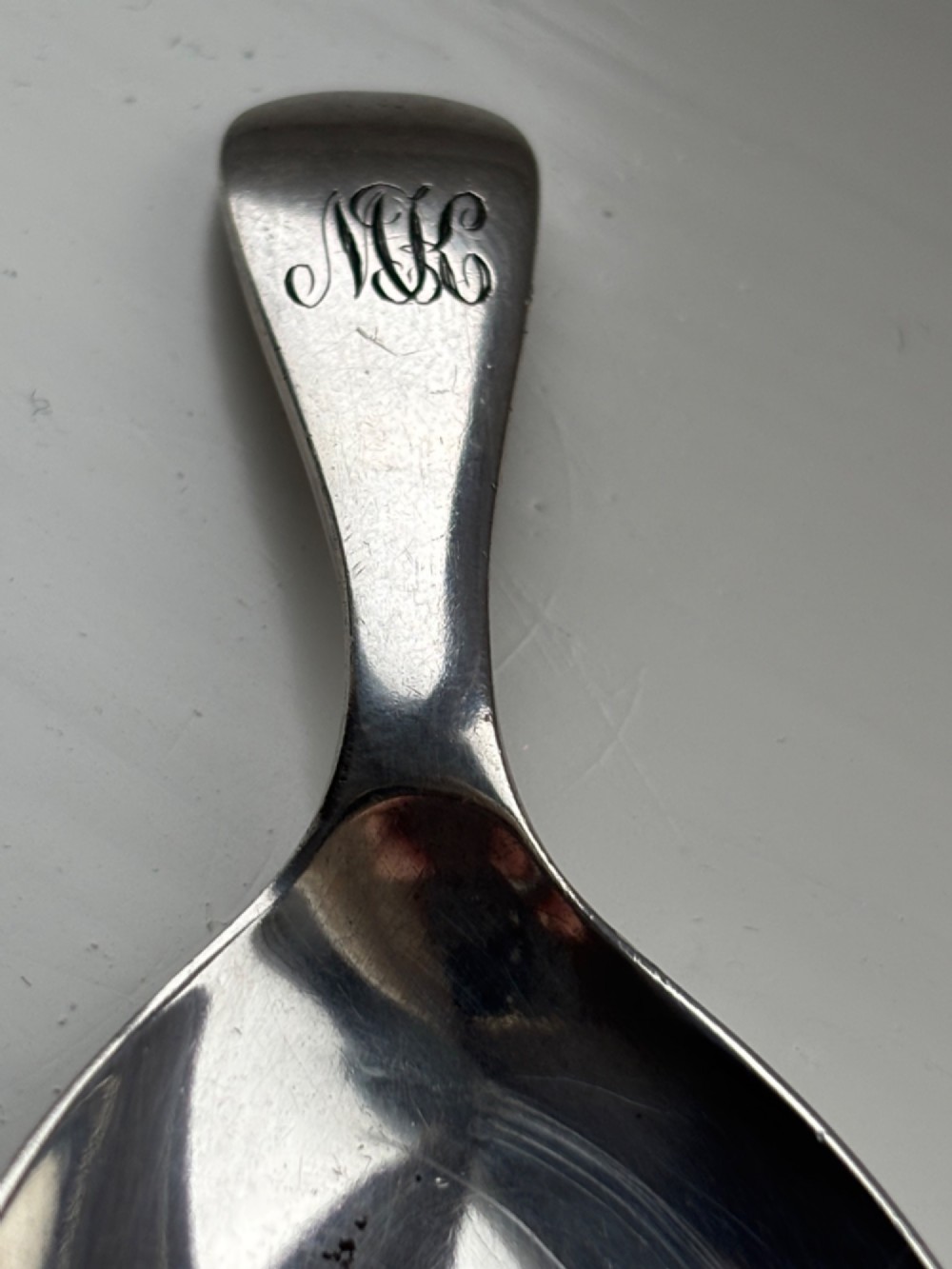A George V sterling silver tea caddy spoon with a wide oval bowl and an engraved monogrammed handle. View VI