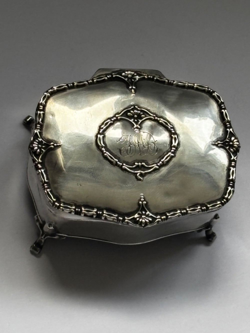 An open George V sterling silver trinket box featuring green velvet lining, gilt lid interior, and cabriole feet. View II