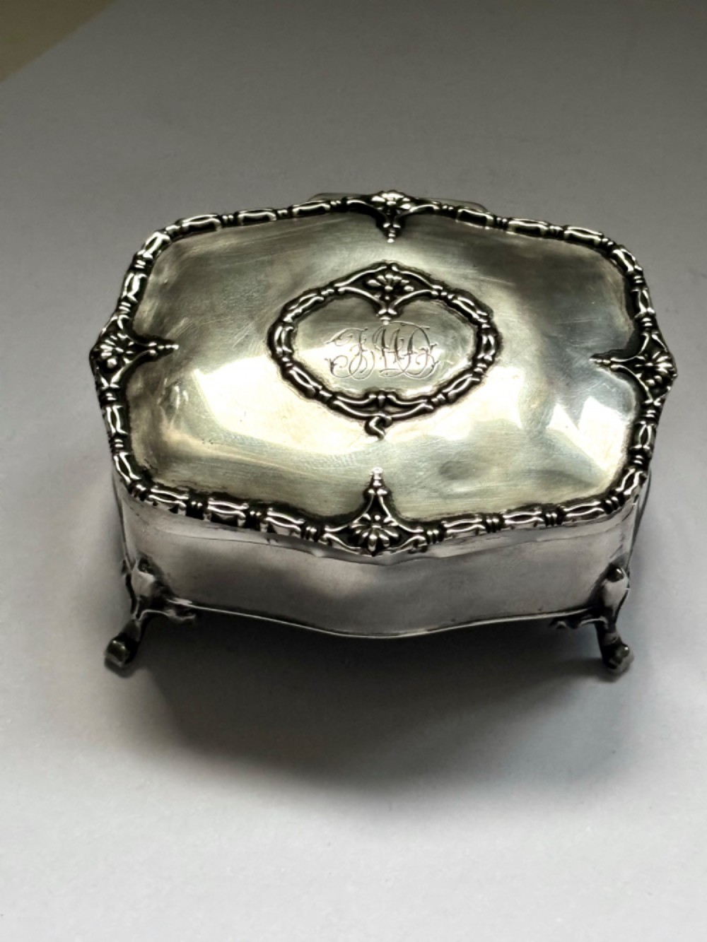 An open George V sterling silver trinket box featuring green velvet lining, gilt lid interior, and cabriole feet. View VI