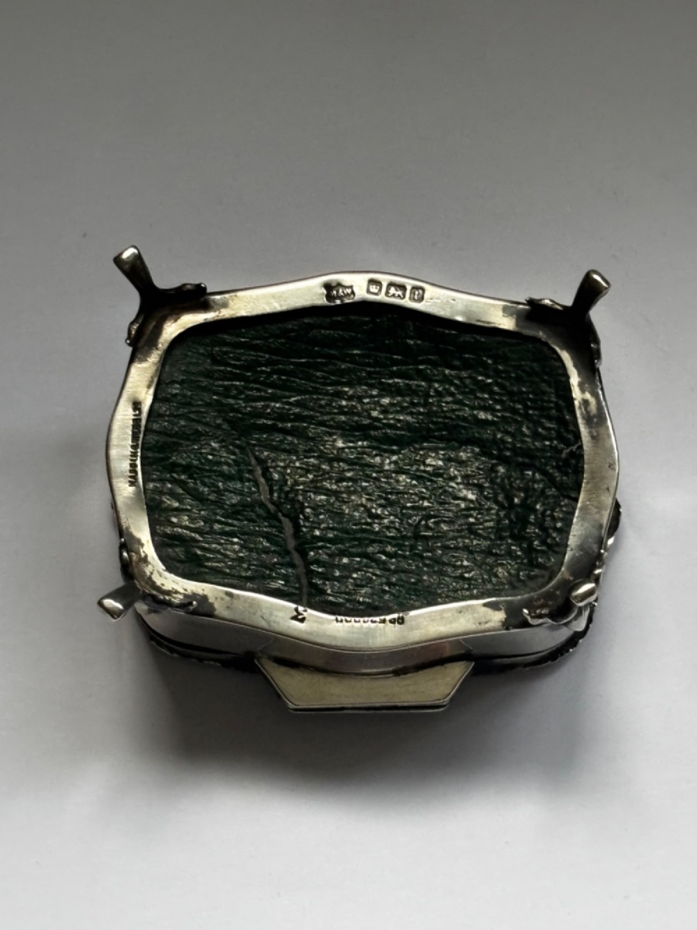 An open George V sterling silver trinket box featuring green velvet lining, gilt lid interior, and cabriole feet. View VII