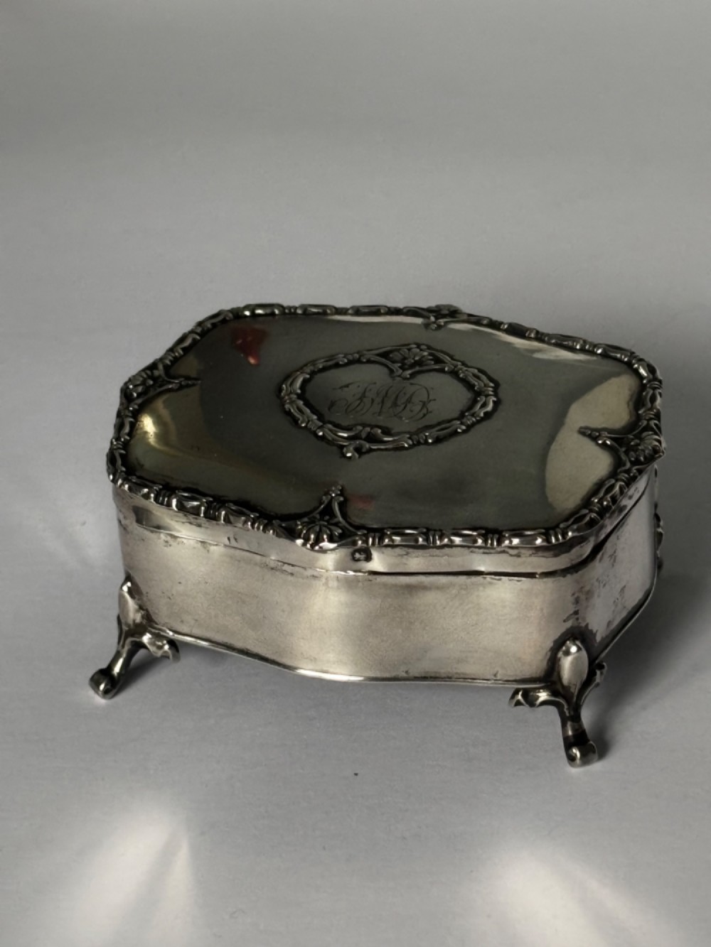 An open George V sterling silver trinket box featuring green velvet lining, gilt lid interior, and cabriole feet. View XI