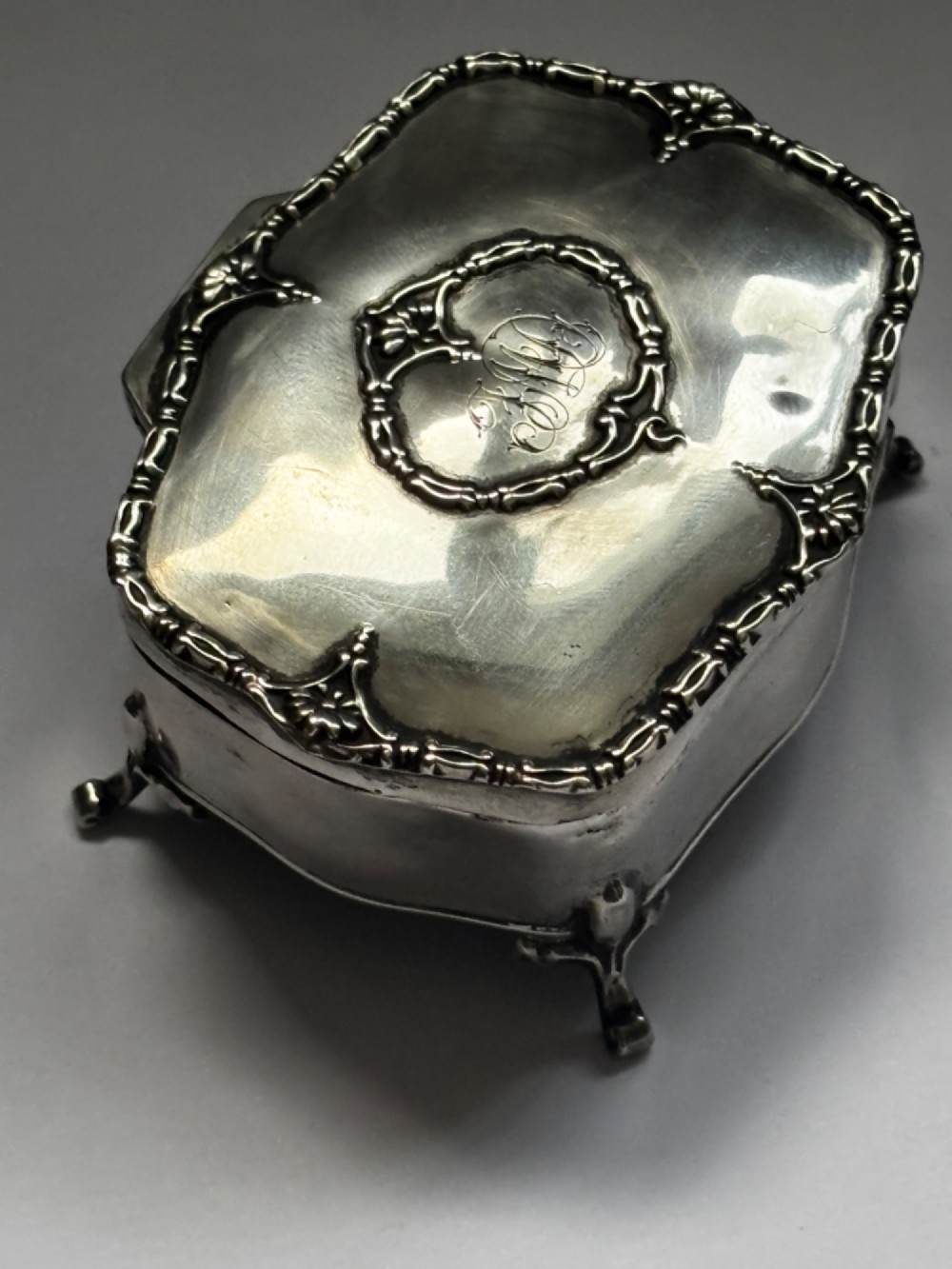 An open George V sterling silver trinket box featuring green velvet lining, gilt lid interior, and cabriole feet. View XII